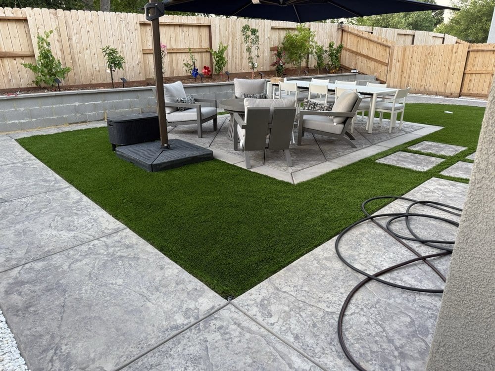 Stamped concrete patio and artificial turf backyard by IronNest Construction