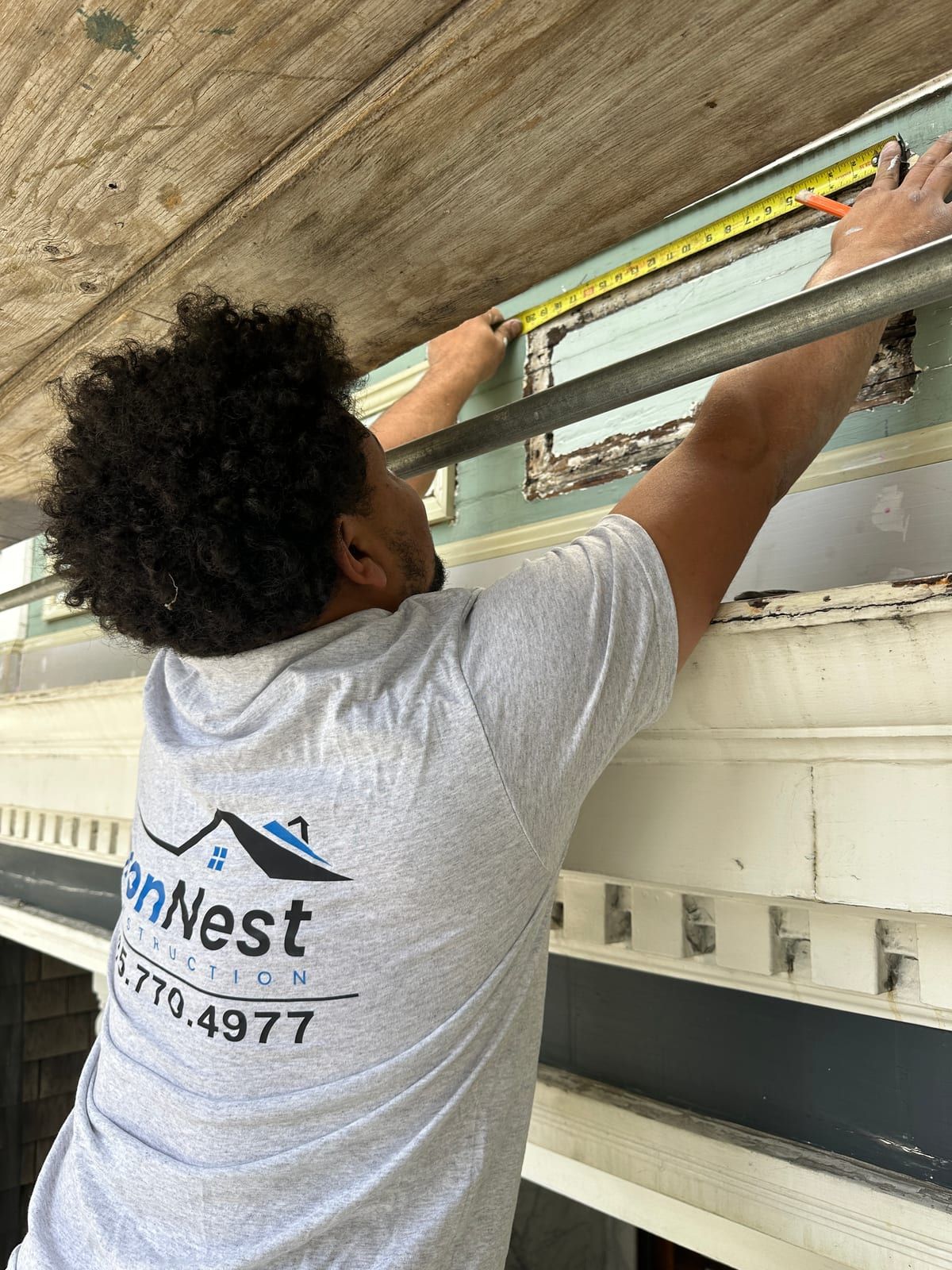 IronNest carpenter measuring damaged Victorian trim before replacement